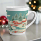 This ceramic glossy latte coffee mug features a vintage winter Christmas illustration of a snowy winter town. There are red houses, a bridge, trees, and two children building a snowman.