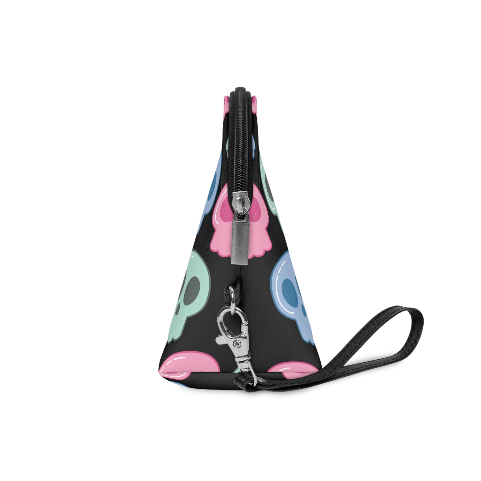 Side view of cute cosmetic makeup travel bag featuring adorable pastel skulls with a black background. The bag has a zipper and a side wristlet.