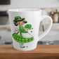 This ceramic glossy latte coffee mug features a midcentury St. Patrick's Day illustration of an adorable girl dresed in green holding a bouquet of shamrocks.