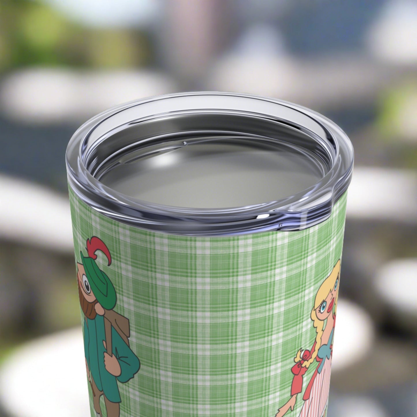 This 10 ounce travel tumbler mug features characters from the Sound of Music Lonely Goatherd song: The Goatherd, the girl in the pale pink coat, and the baby goat. The background is green plaid. The mug comes with a plastic sipping lid.