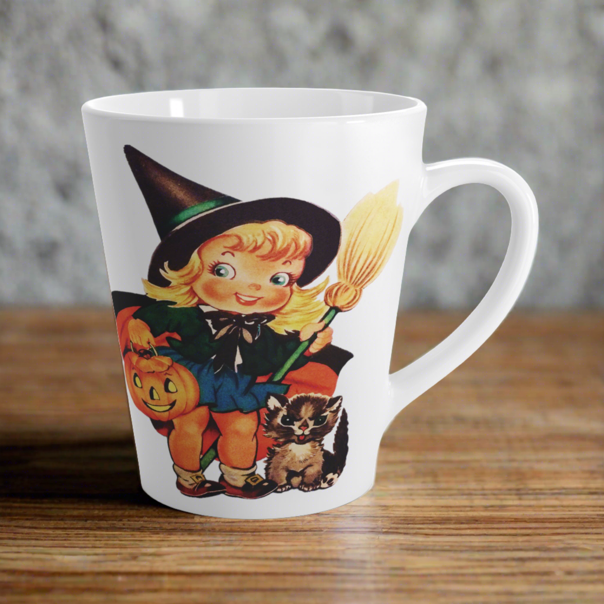 This ceramic glossy latte coffee cup features a retro vintage Halloween print of a young witch holding a broom and jack o lantern with a little brown cat sitting next to her.