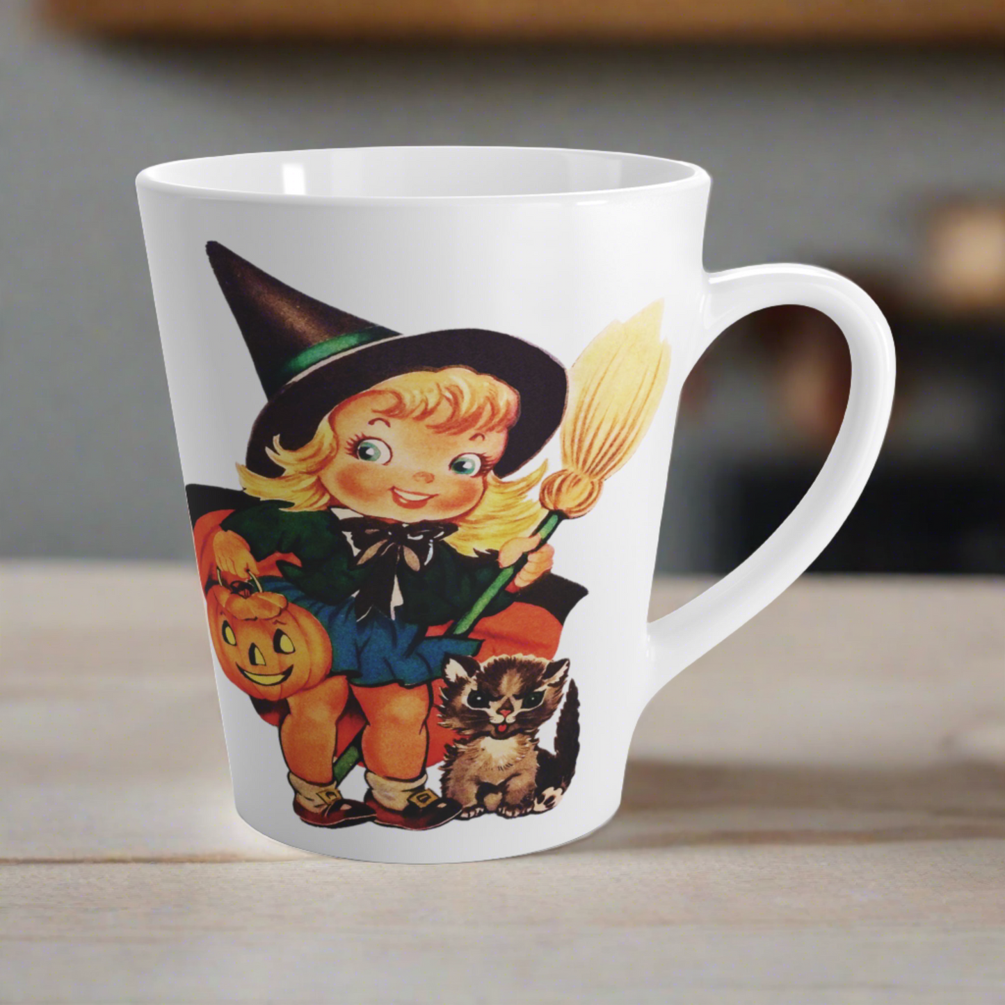 This ceramic glossy latte coffee cup features a retro vintage Halloween print of a young witch holding a broom and jack o lantern with a little brown cat sitting next to her.