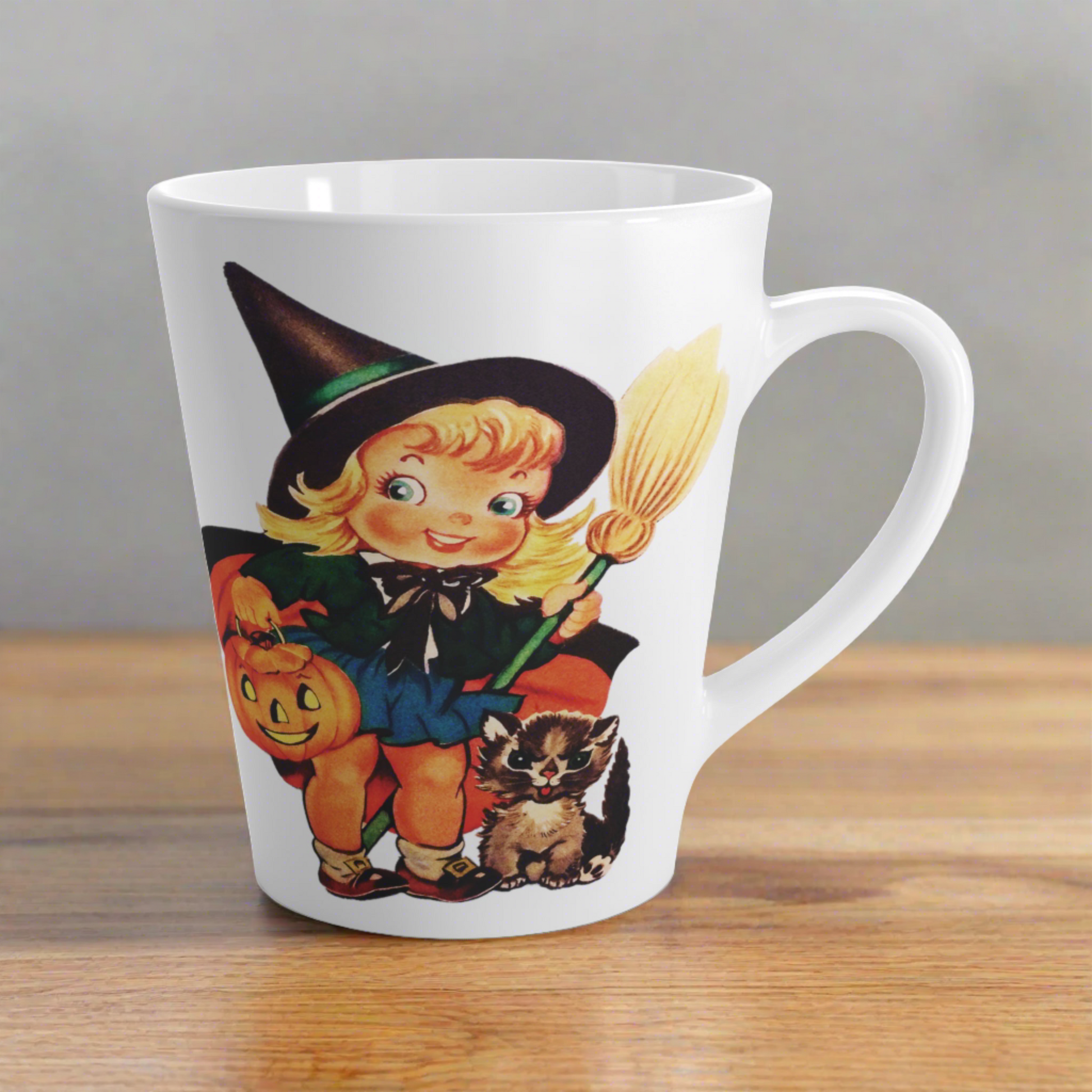 This ceramic glossy latte coffee cup features a retro vintage Halloween print of a young witch holding a broom and jack o lantern with a little brown cat sitting next to her.