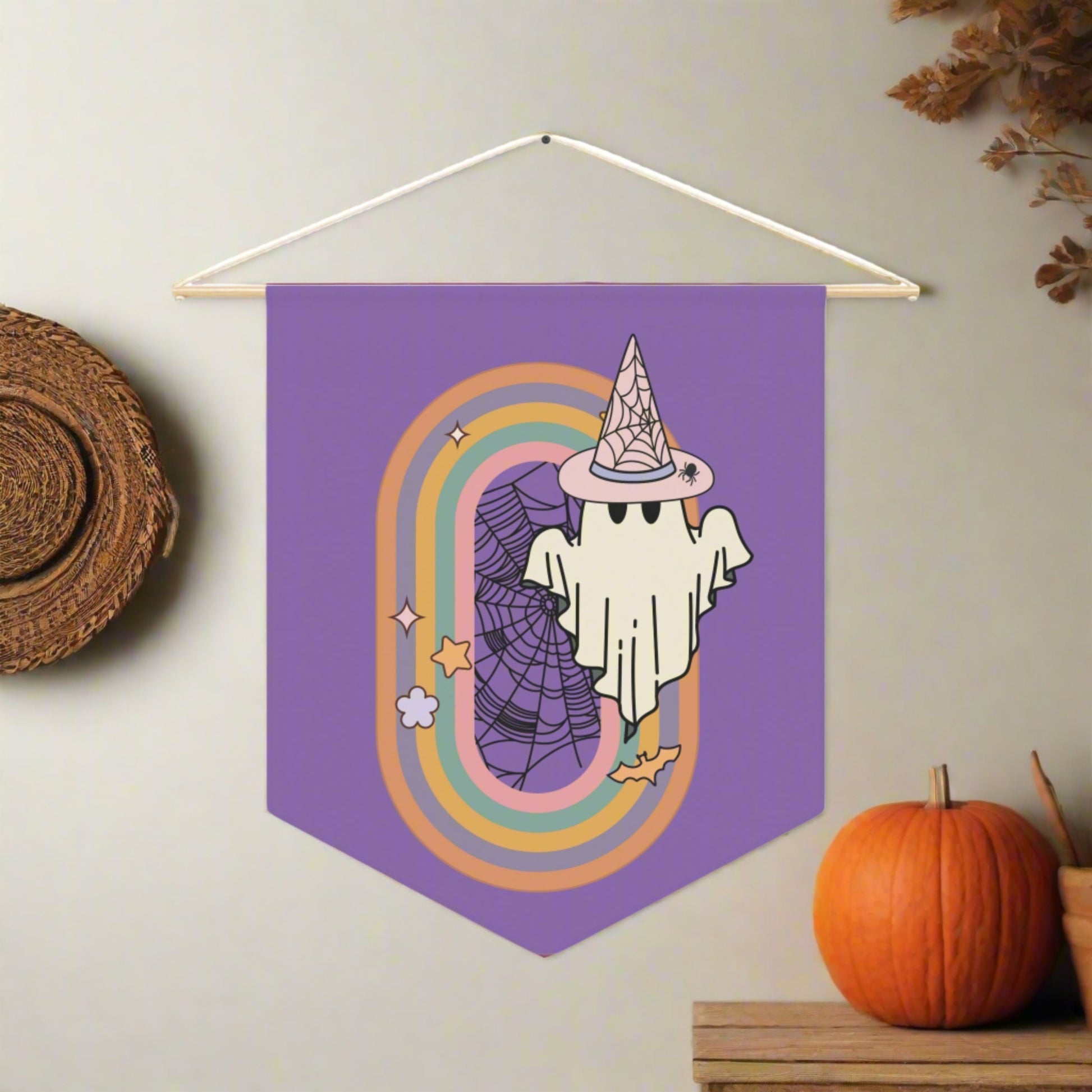 This purple pennant banner flag wall hanging features a retro boho pastel gothic style print of a ghost wearing a witch hat with a rainbow and spider web.