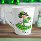 This ceramic glossy latte coffee mug features a midcentury St. Patrick's Day illustration of an adorable girl dresed in green holding a bouquet of shamrocks.