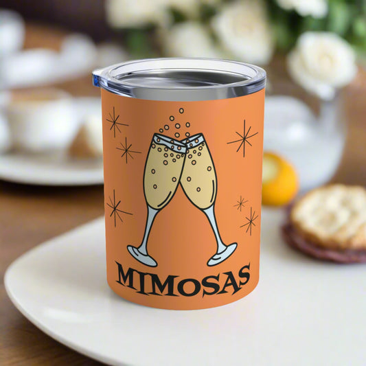 This orange 10 ounce stainless steel vacuum insulated tumbler mug features an atomic era style design of toasting champagne glasses with stars and the word Mimosas underneath the flutes.