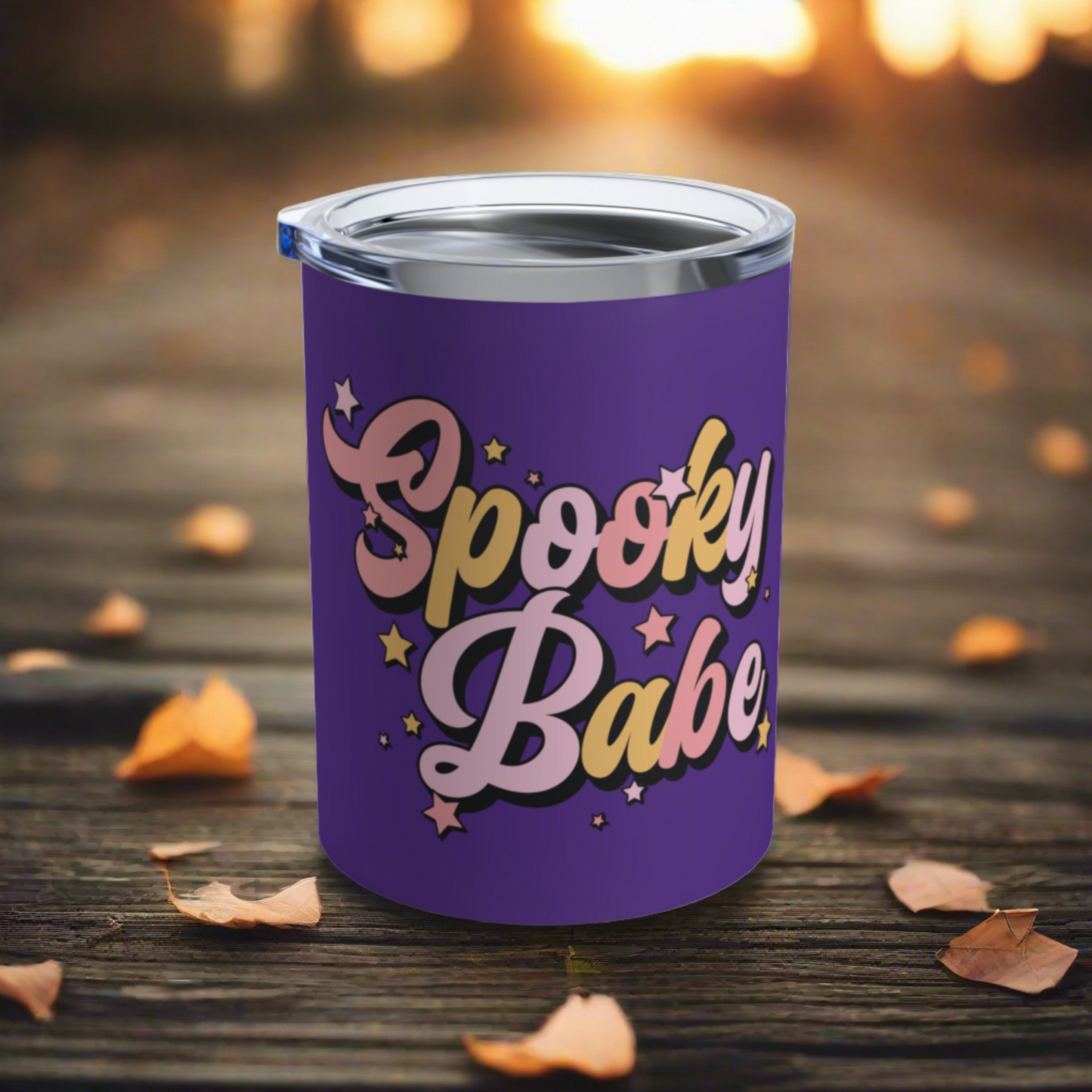 This 10 ounce purple stainless steel travel tumbler mug says Spooky Babe in pinks and yellows with stars.