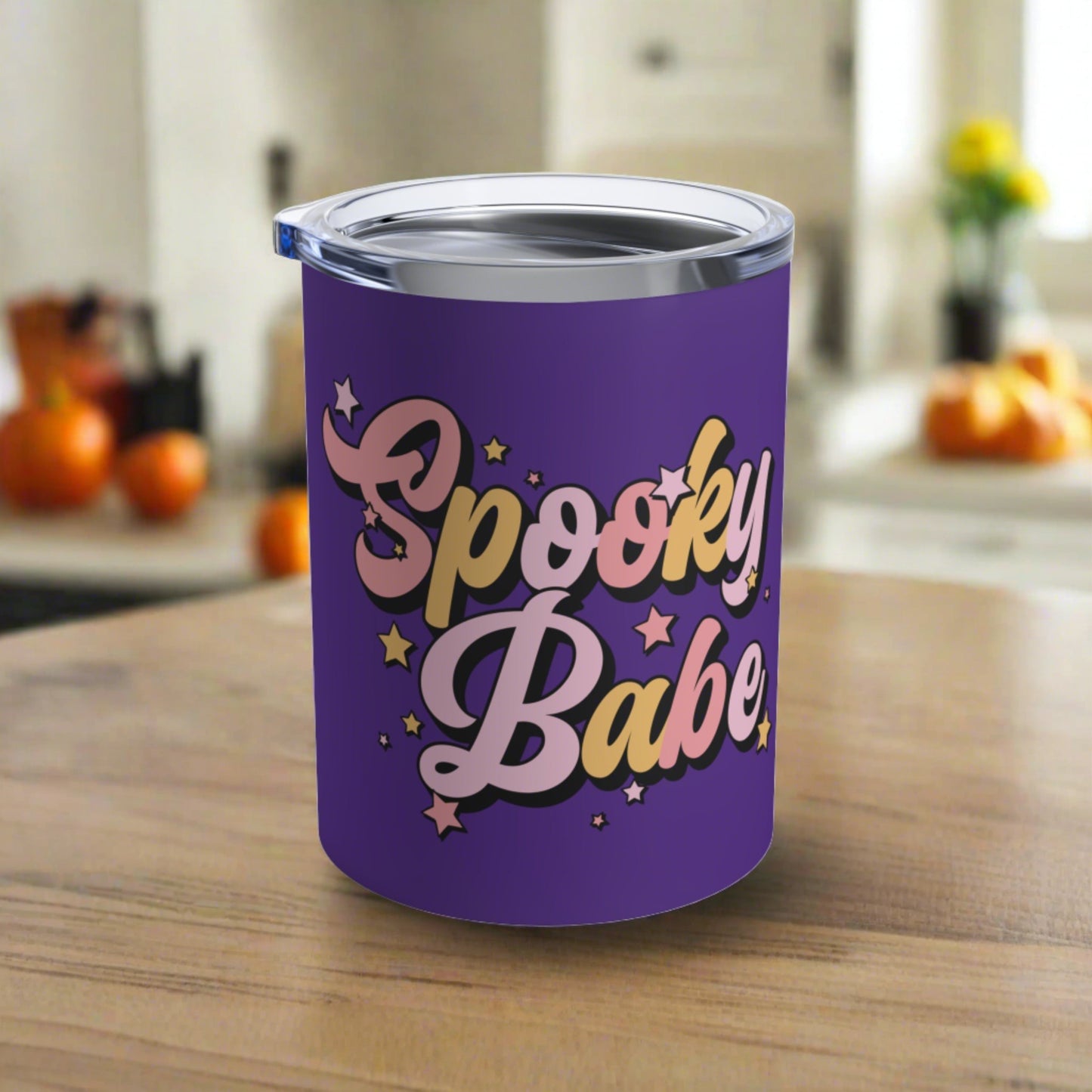 This 10 ounce purple stainless steel travel tumbler mug says Spooky Babe in pinks and yellows with stars.