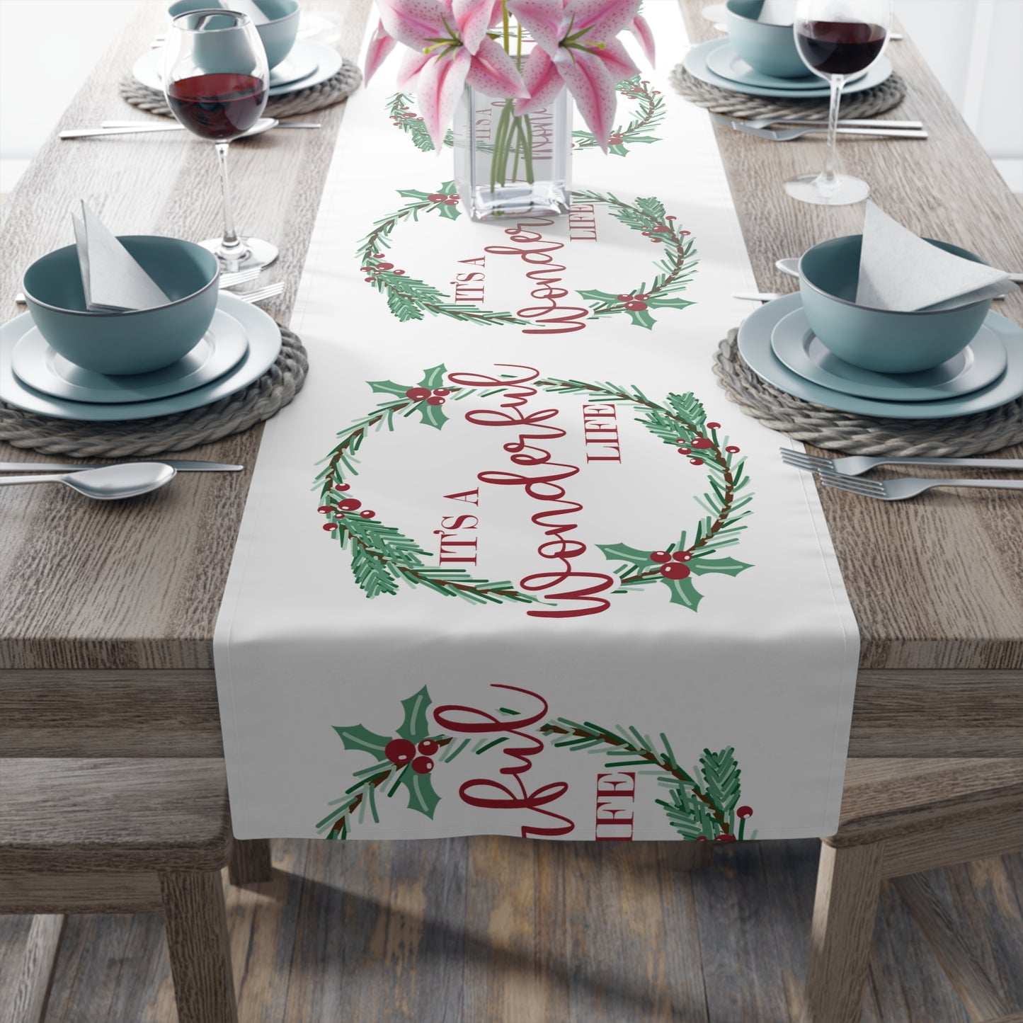 This white Christmas table runner features red lettering that says It's A Wonderful Life inside a holly berry wreath.