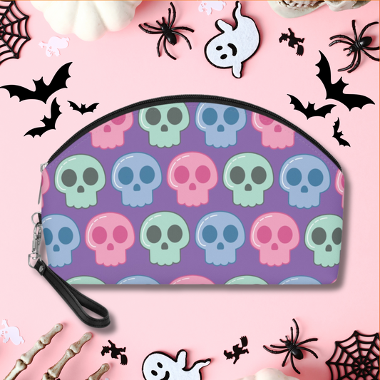 This purple cosmetic makeup bag features pastel green, blue and pink skulls. It has a black zipper and hook on wristlet strap.