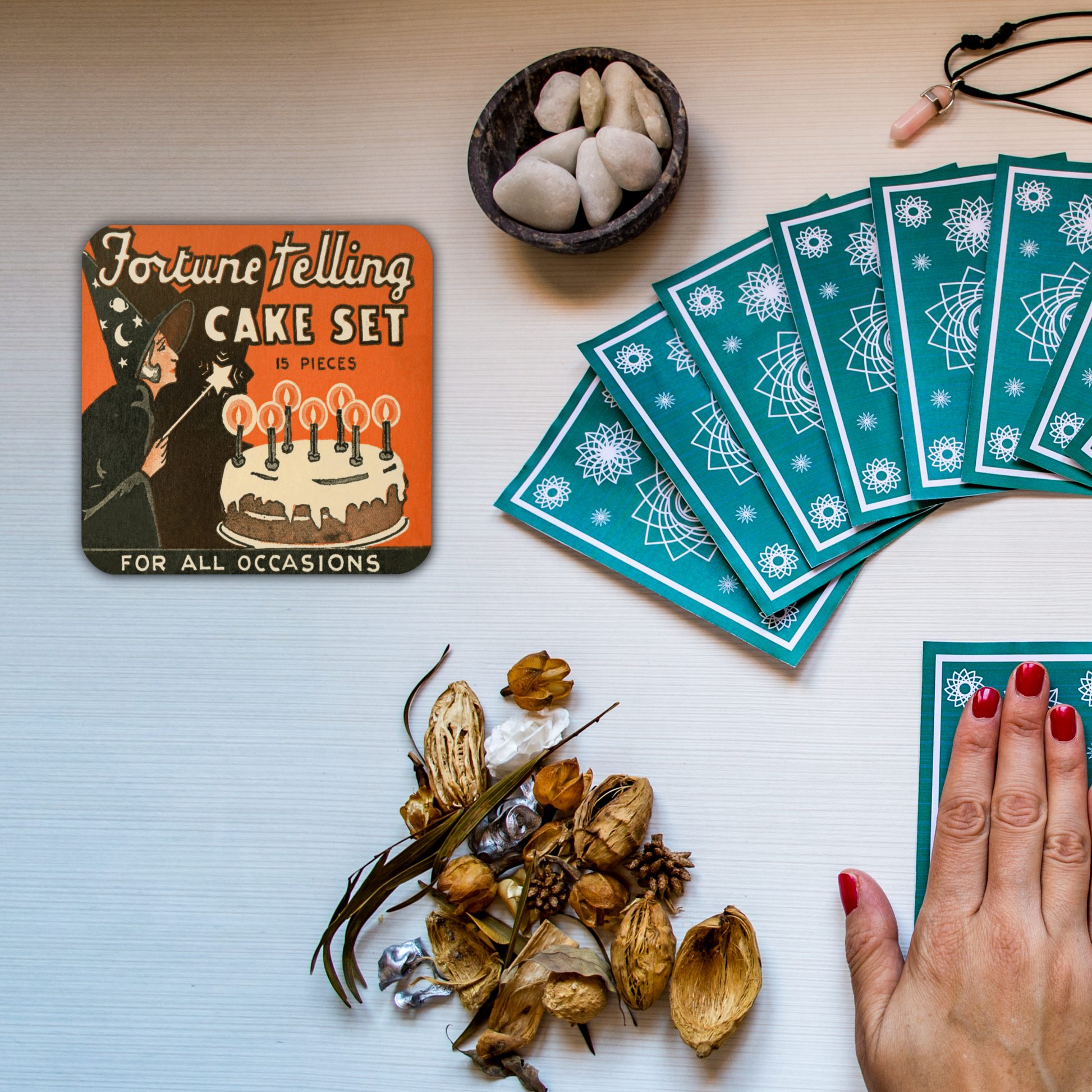 This square cork-back coaster features a retro Halloween illustration that says Fortune Telling Cake Set 15 pieces. There is a witchholding a star magic wand that she is waving over her cake with candles.