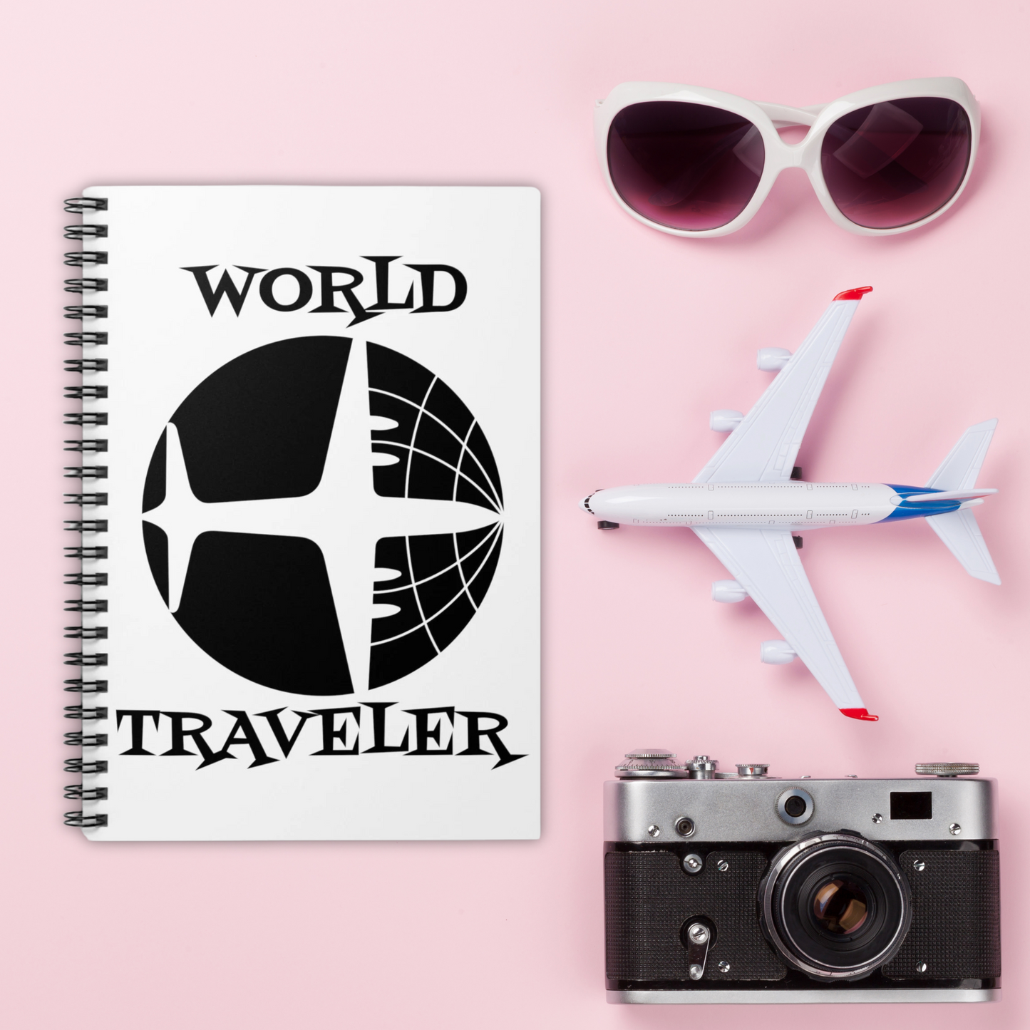 This white spiral journal features a retro print of an airplane and the globe with atomic era lettering that says World Traveler.