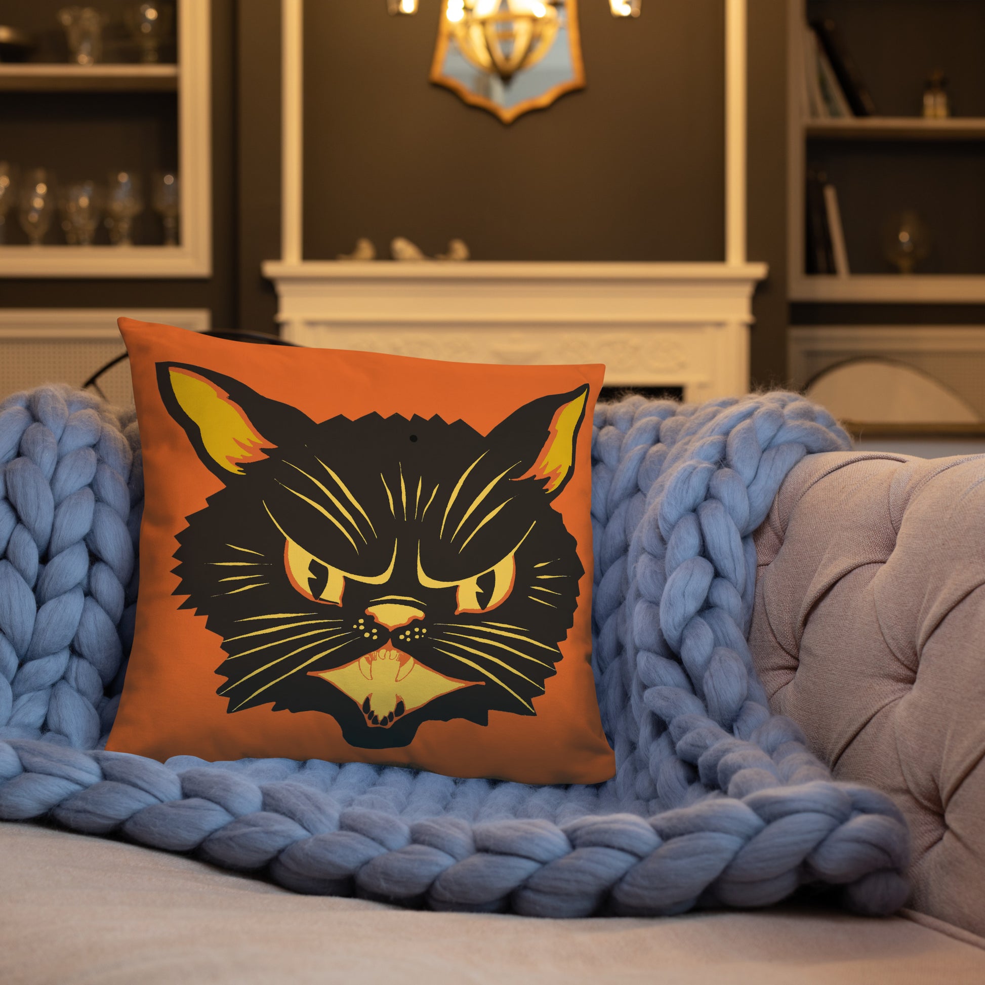 This orange square pillow features a retro midcentury Halloween print of a Black Cat with orange and yellow eyes, ears, nose, whiskers and mouth.