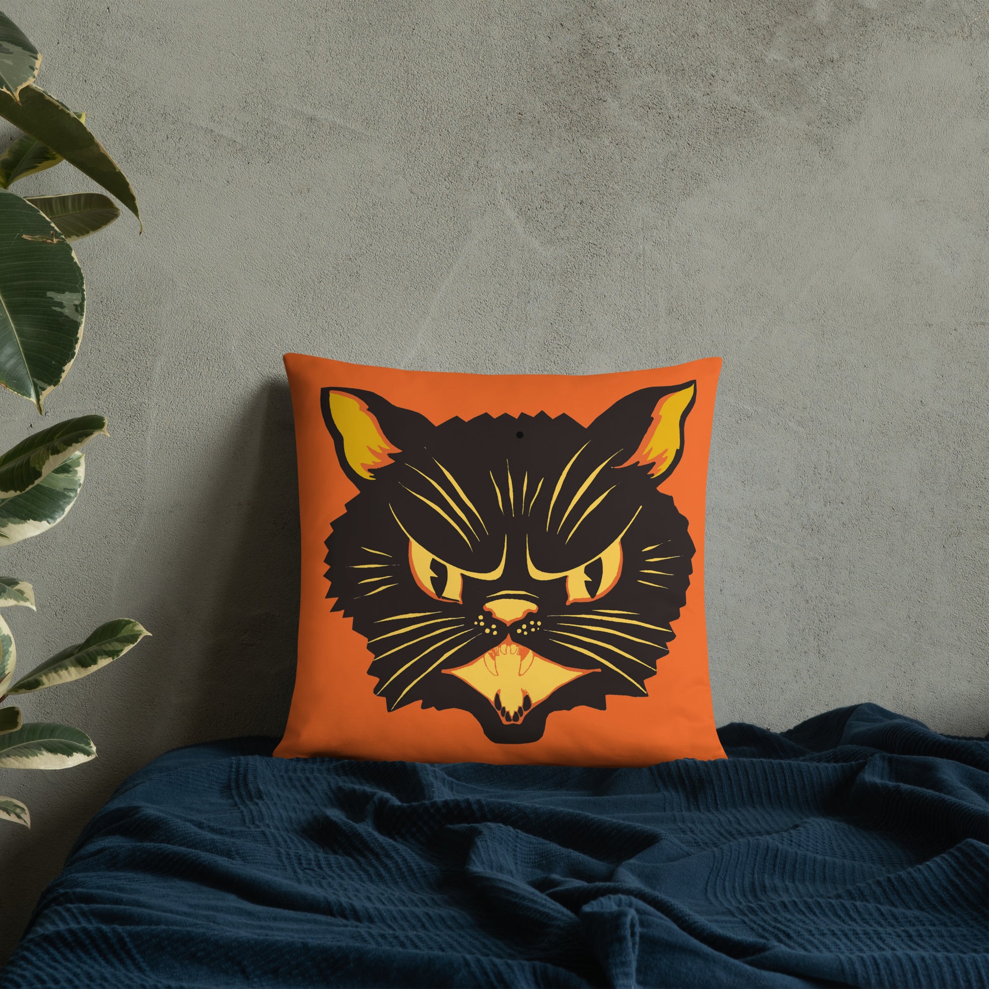 This orange square pillow features a retro midcentury Halloween print of a Black Cat with orange and yellow eyes, ears, nose, whiskers and mouth.