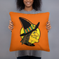 This orange square pillow features a retro Halloween illustration of a witch wearing her pointy hat with a yellow full moon behind her profile.