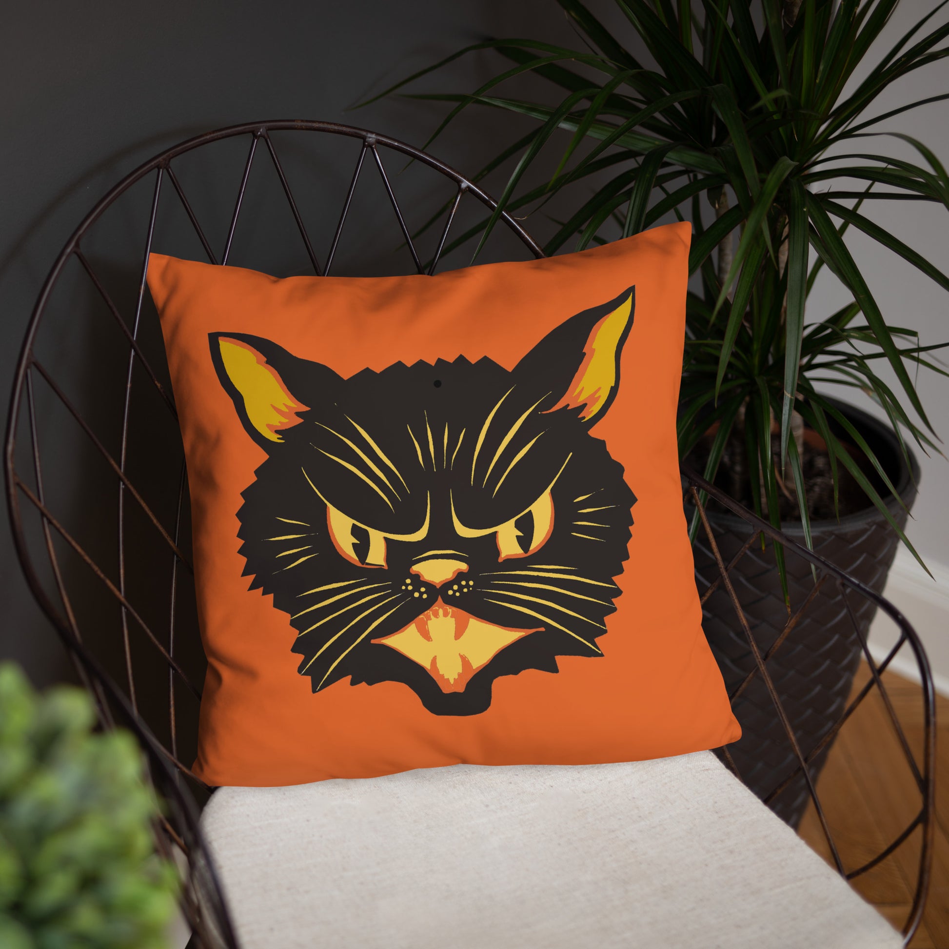 This orange square pillow features a retro midcentury Halloween print of a Black Cat with orange and yellow eyes, ears, nose, whiskers and mouth.