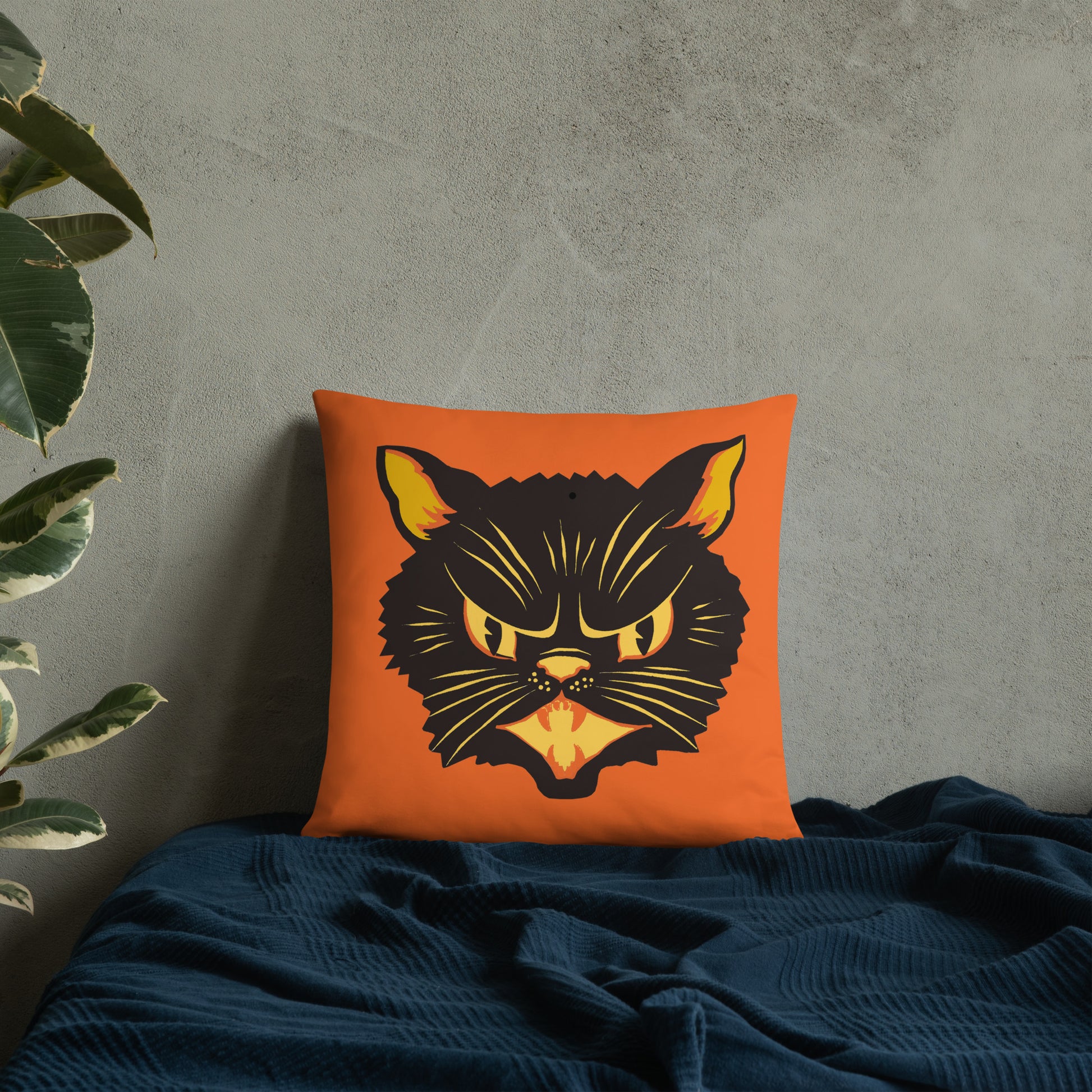 This orange square pillow features a retro midcentury Halloween print of a Black Cat with orange and yellow eyes, ears, nose, whiskers and mouth.