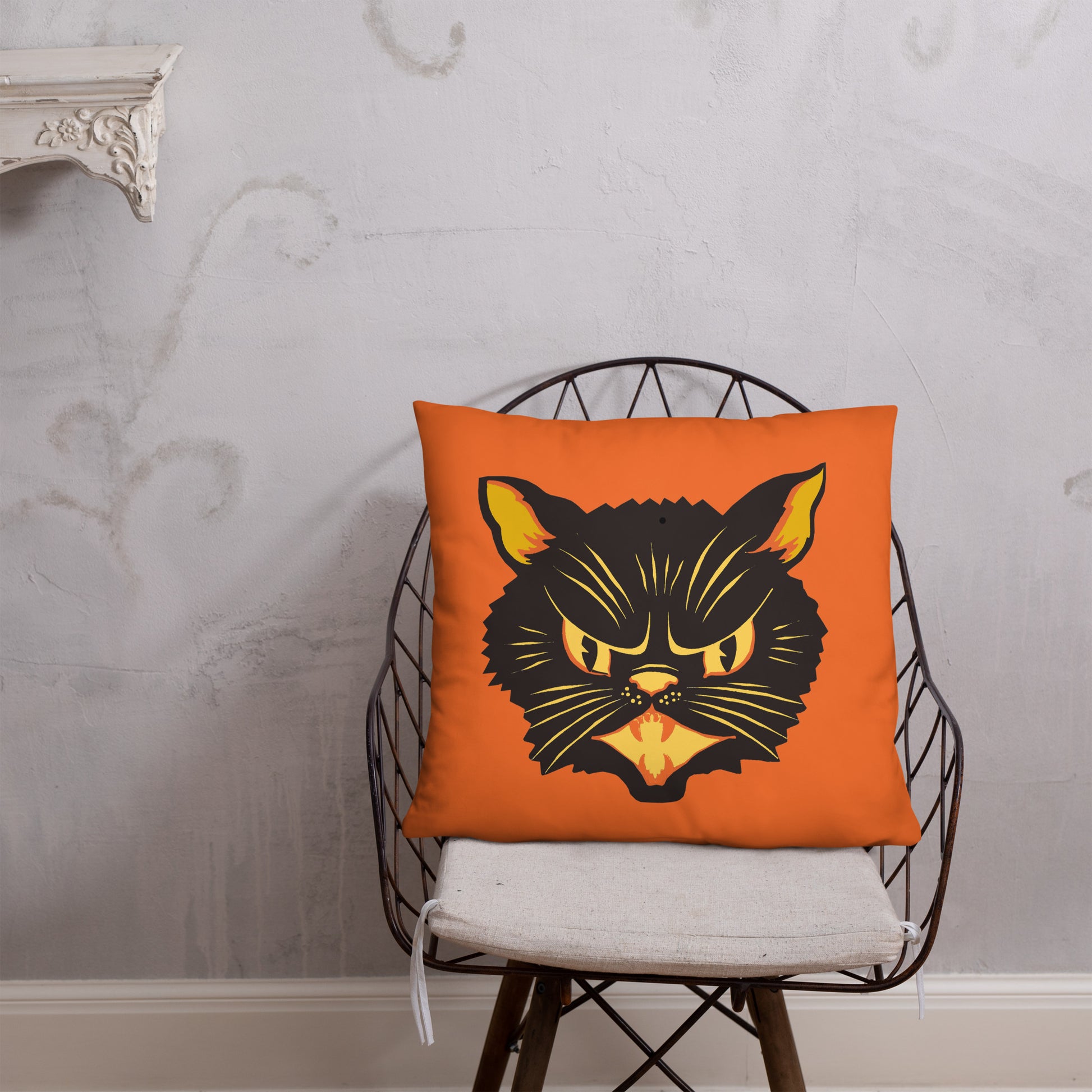 This orange square pillow features a retro midcentury Halloween print of a Black Cat with orange and yellow eyes, ears, nose, whiskers and mouth.