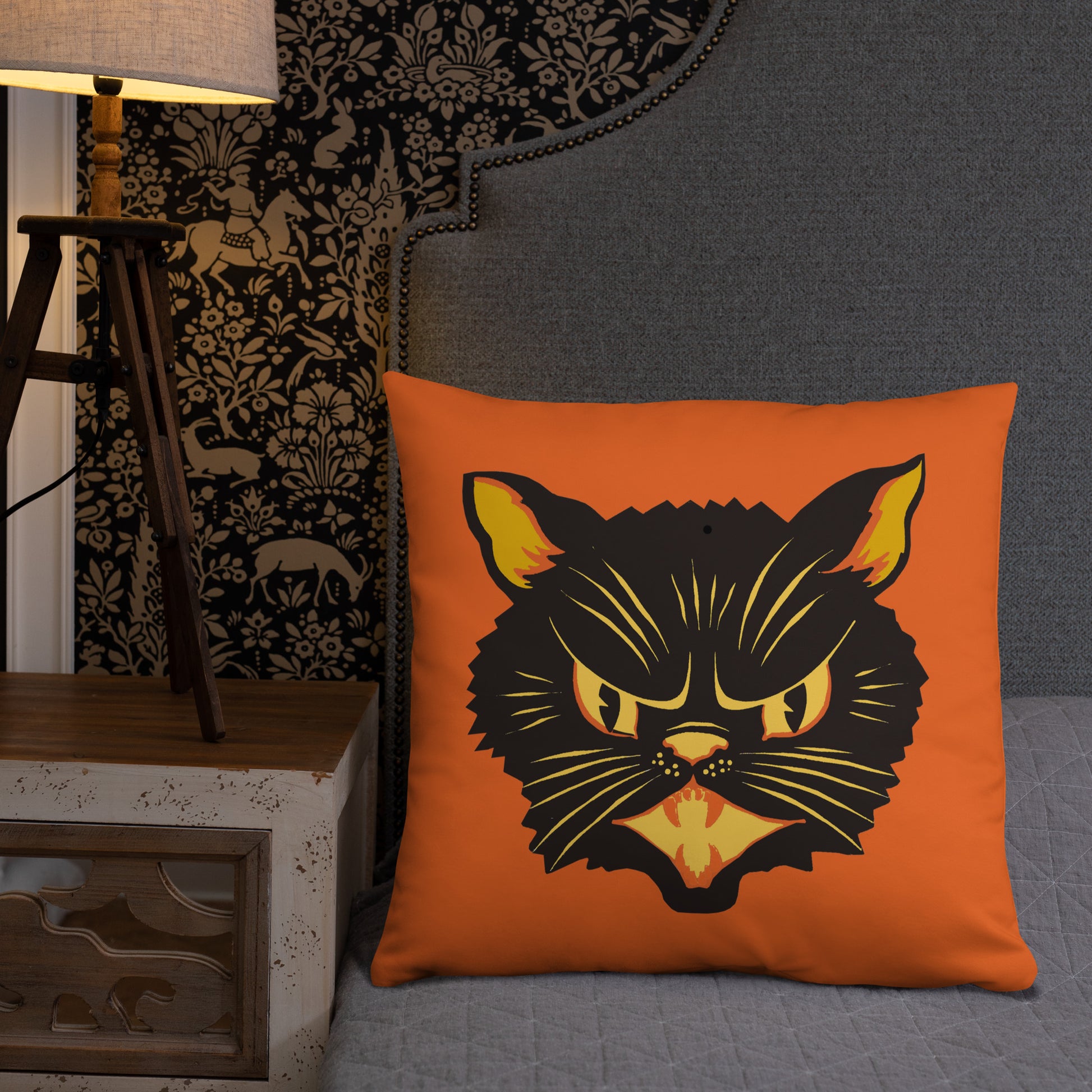 This orange square pillow features a retro midcentury Halloween print of a Black Cat with orange and yellow eyes, ears, nose, whiskers and mouth.