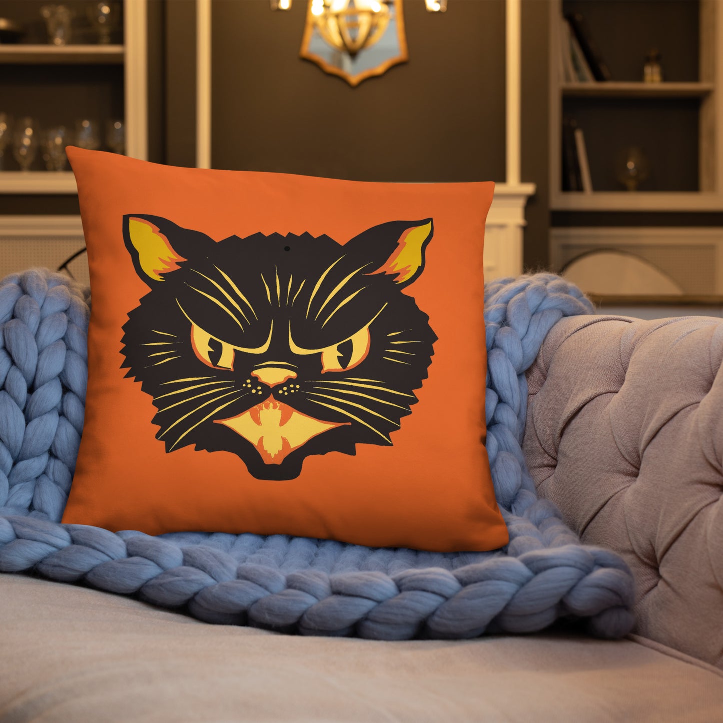 This orange square pillow features a retro midcentury Halloween print of a Black Cat with orange and yellow eyes, ears, nose, whiskers and mouth.