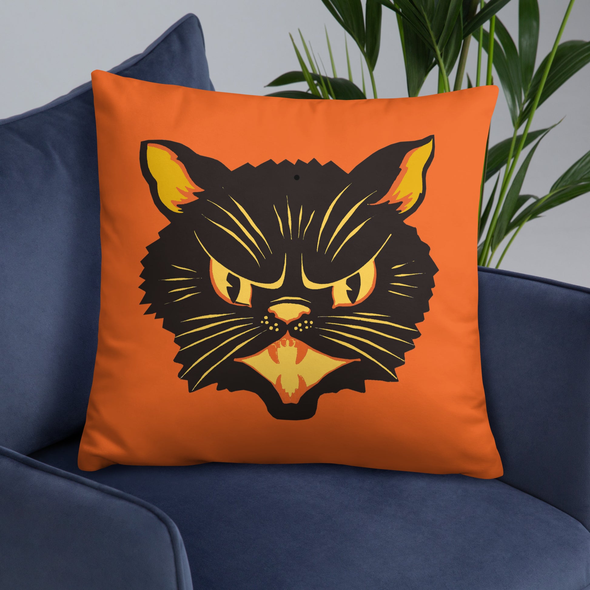 This orange square pillow features a retro Halloween illustration of a black cat with orange and yellow ears, eyes, nose and mouth.