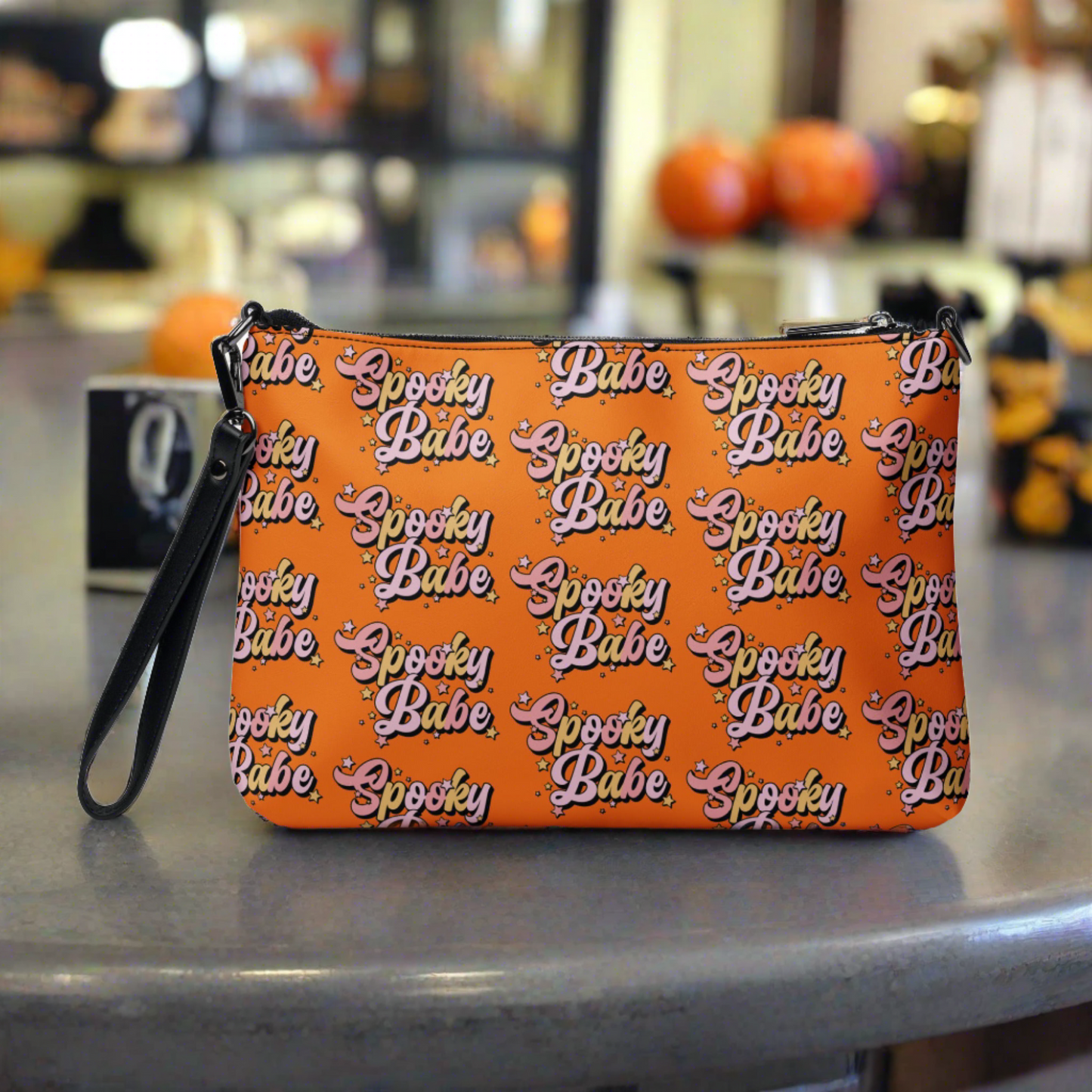 This orange crossbody purse features a retro Barbie style type of lettering that says Spooky Babe in fall pastel colors with stars.