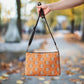 This orange crossbody purse features a skeleton hand making a peace sign surrounded by bats, flowers and peace signs.