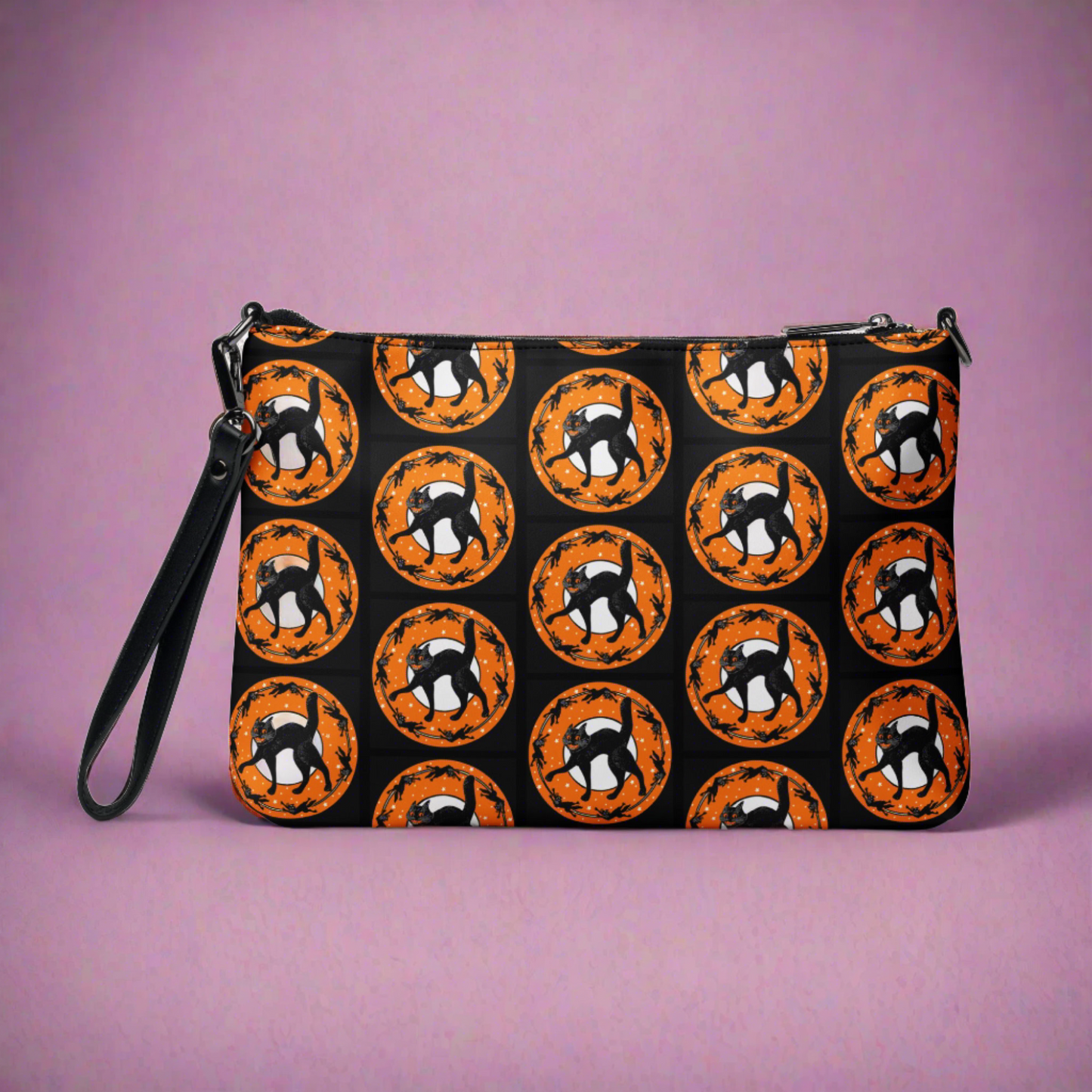 The back of this purse features the retro Halloween print of a black cat surrounded by little black cats in a circle with a full moon and orange circle with white stars. It is patterned on the back with the main print on the front.