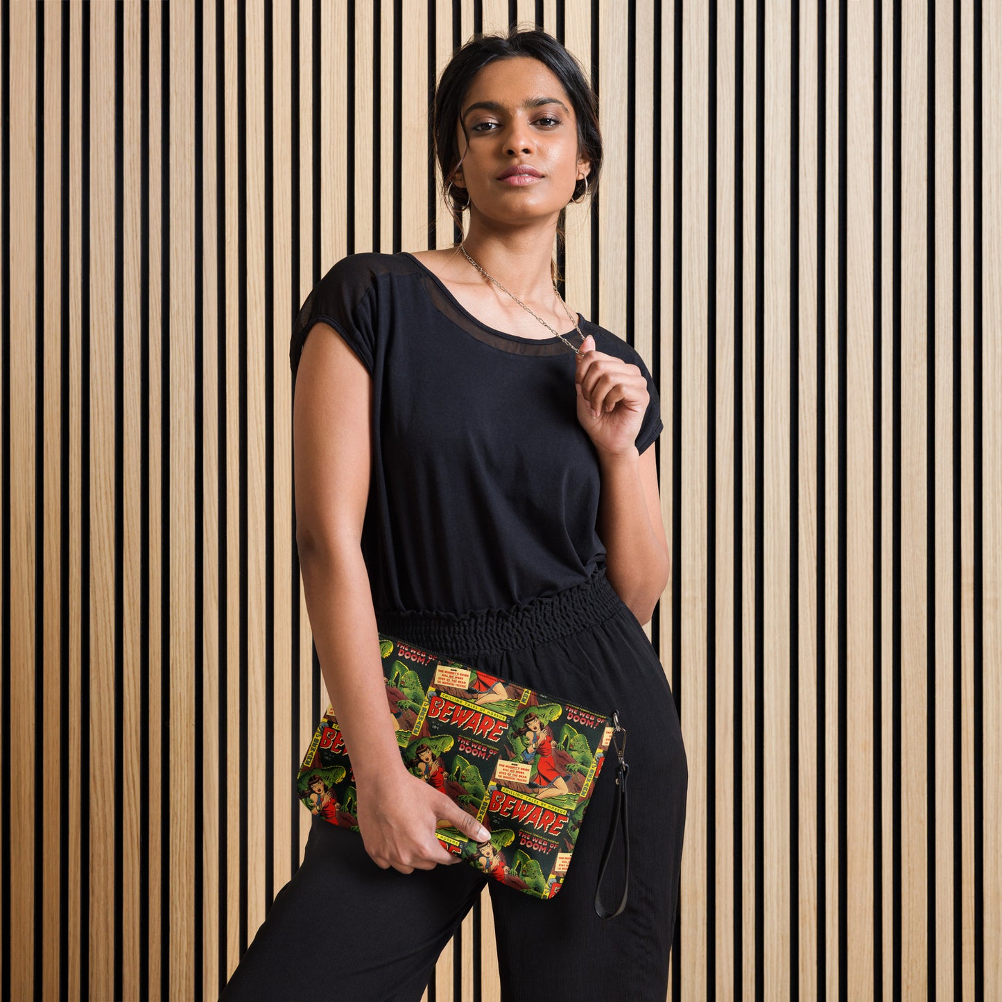 This crossbody bag comes with a wristlet option and is featured in this photo. The print is a retro comic that is Beware the Web of Doom with a gothic noir print of green creatures and a scared woman in red. This is printed in a staggered pattern.