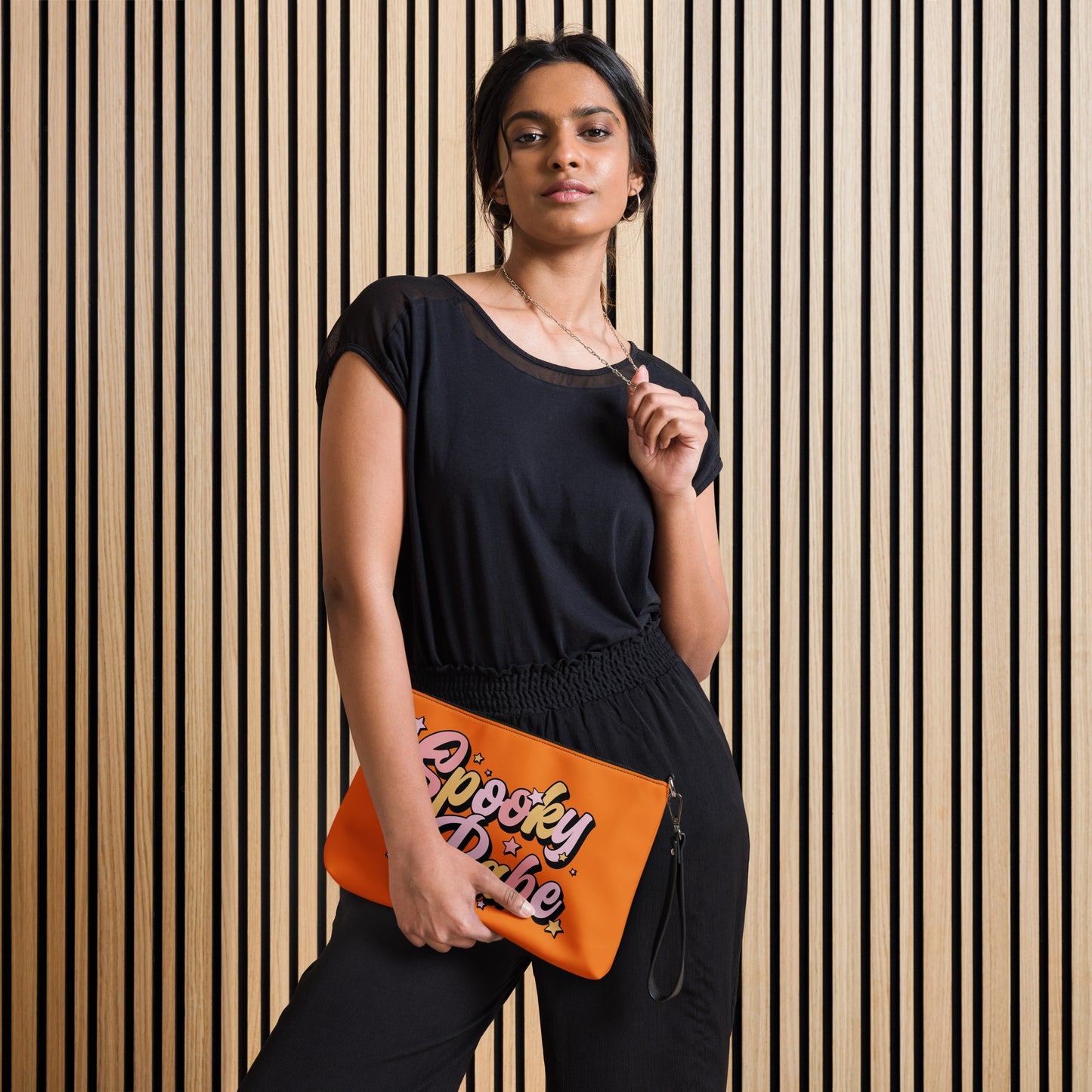 This orange crossbody purse features a retro Barbie style type of lettering that says Spooky Babe in fall pastel colors with stars.