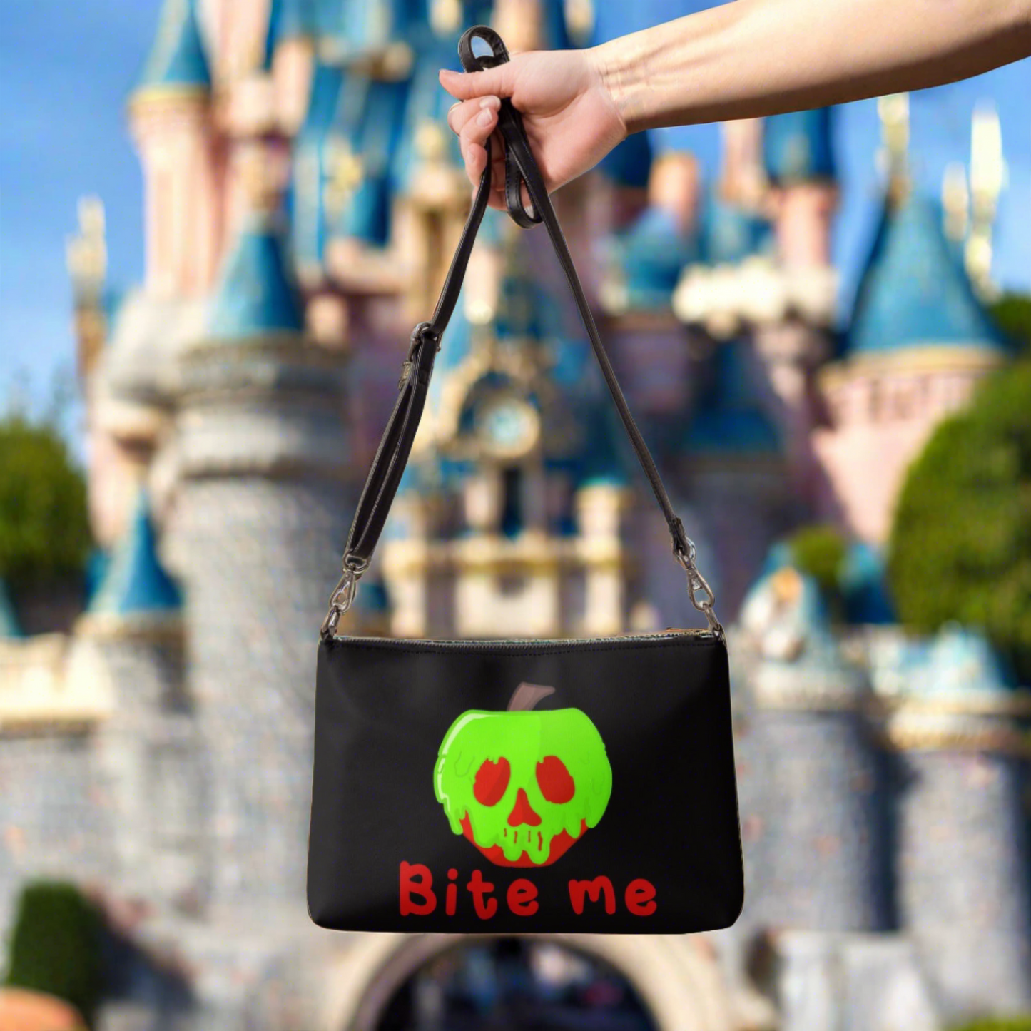 This black crossbody purse features a large red apple dipped in green poison with the words Bite Me underneath and the back is a small size in a patterned print.