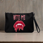 This crossbody purse features pink gothic lettering that says Bite Me with bloody vampire lips and fangs below. The bag is black with a black strap.