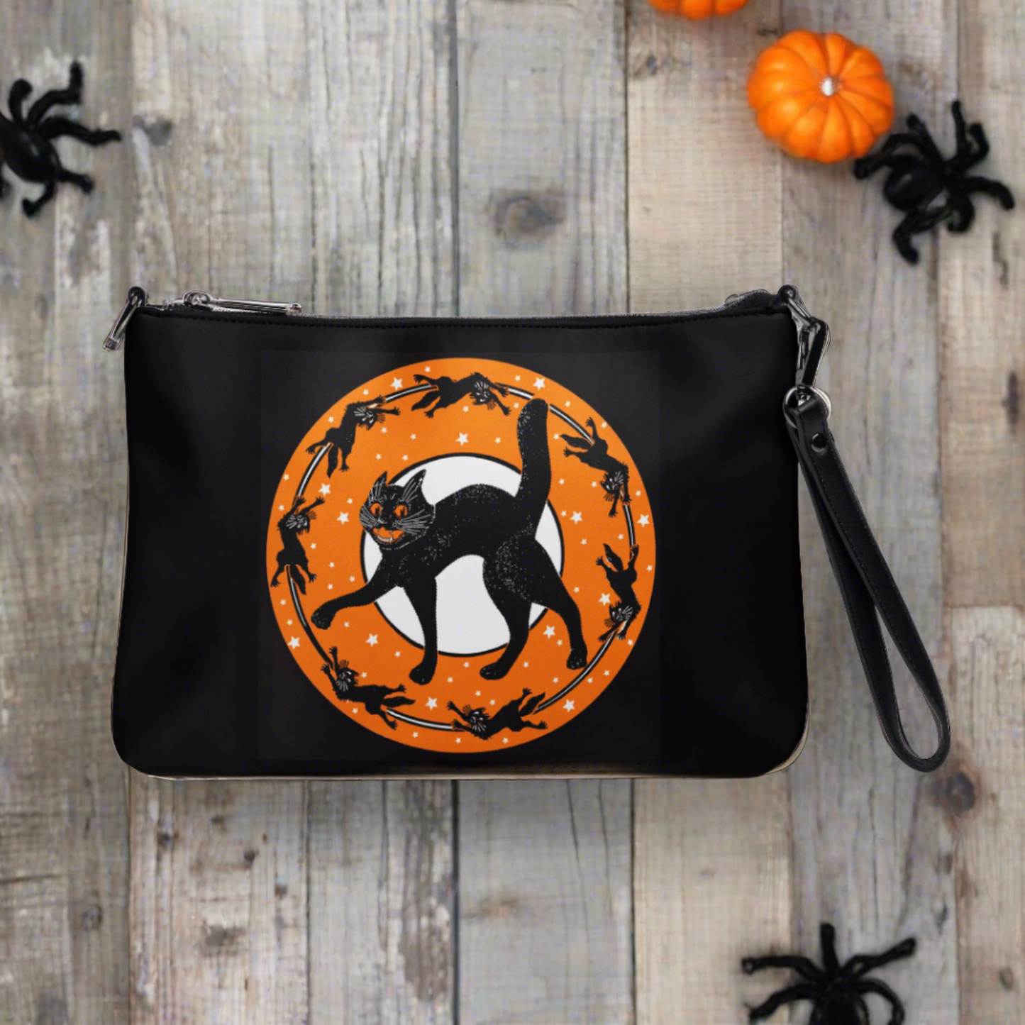 The back of this purse features the retro Halloween print of a black cat surrounded by little black cats in a circle with a full moon and orange circle with white stars. It is patterned on the back with the main print on the front.