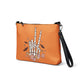 This orange crossbody purse features a skeleton hand making a peace sign surrounded by bats, flowers and peace signs.