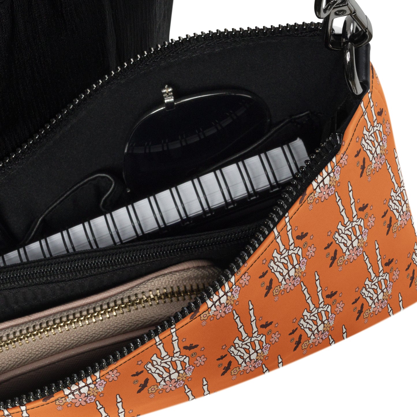 This orange crossbody purse features a skeleton hand making a peace sign surrounded by bats, flowers and peace signs.