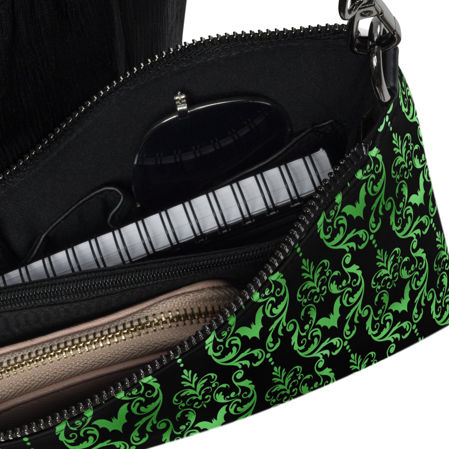 This black crossbody shoulder bag converts into a large wristlet clutch features a retro wallpaper print of green bats and swirls.