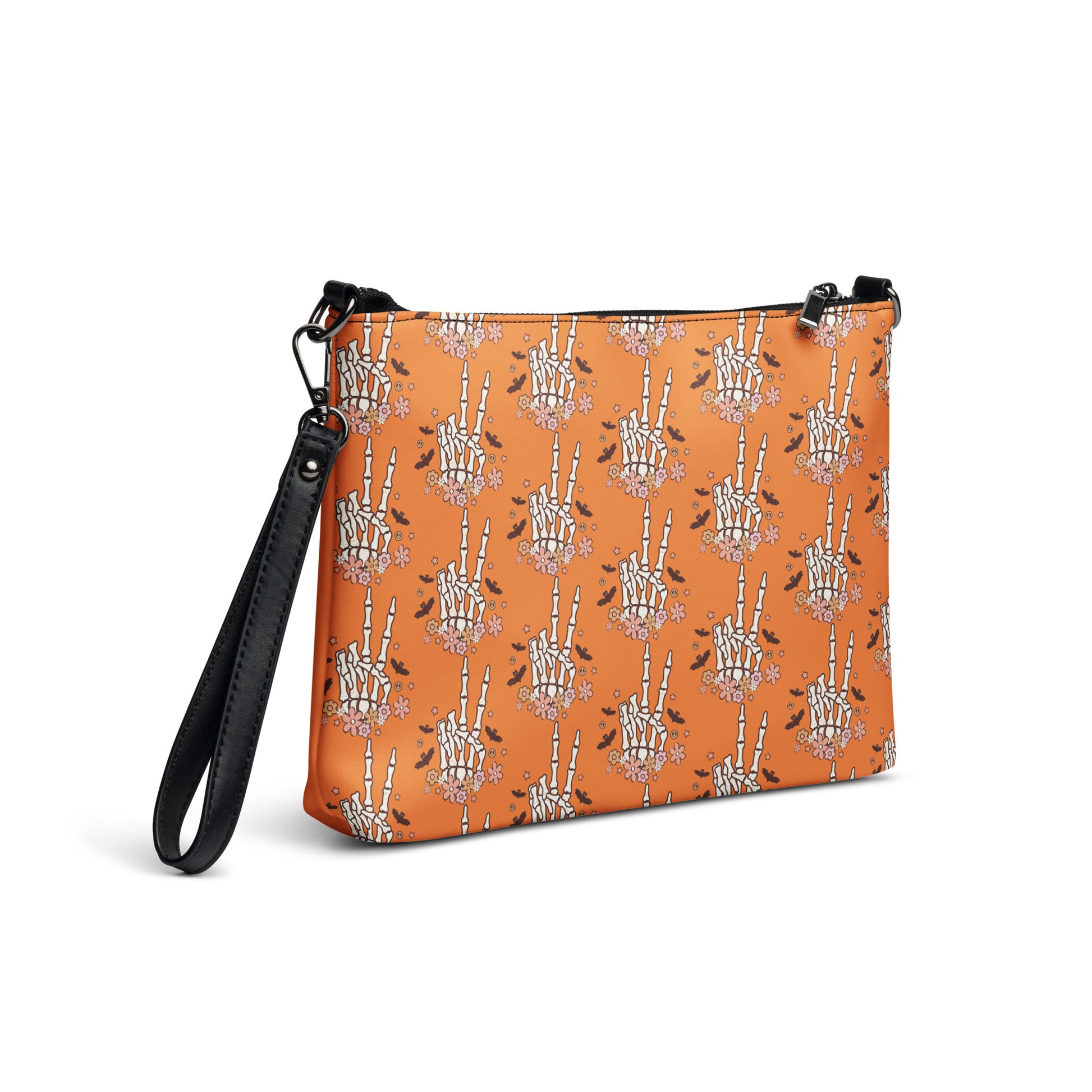 This orange crossbody purse features a skeleton hand making a peace sign surrounded by bats, flowers and peace signs.