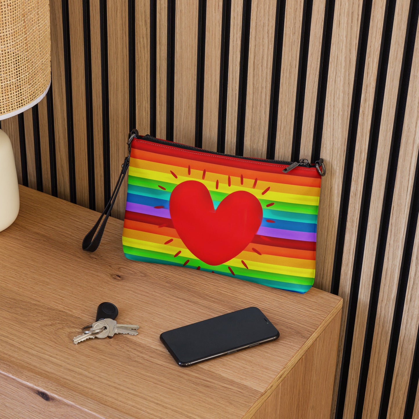 This shoulder crossbody purse converts to a large wristlet clutch. It features horizontal rainbow stripes with a large red heart in the center.