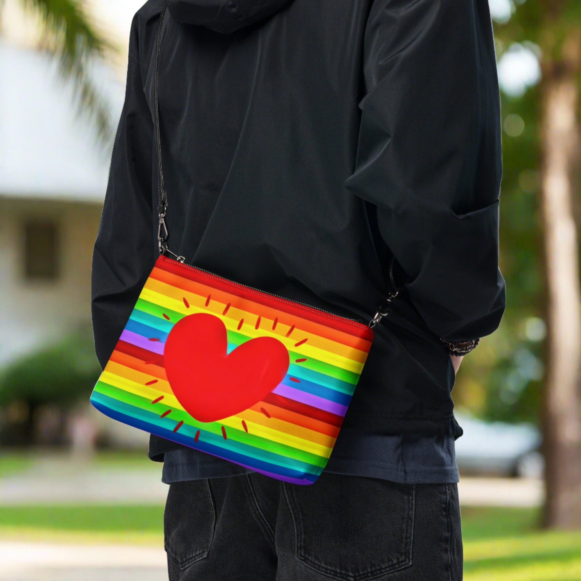 This shoulder crossbody purse converts to a large wristlet clutch. It features horizontal rainbow stripes with a large red heart in the center.