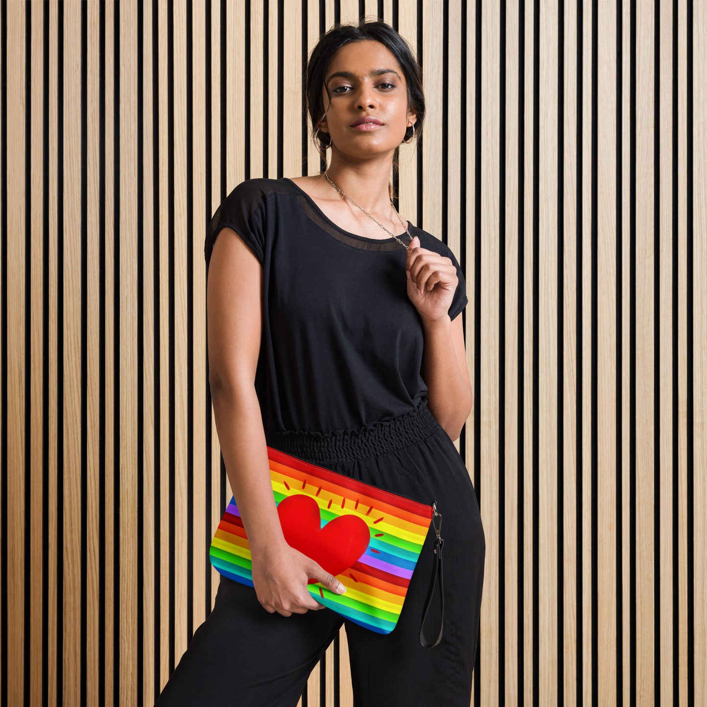 This shoulder crossbody purse converts to a large wristlet clutch. It features horizontal rainbow stripes with a large red heart in the center.