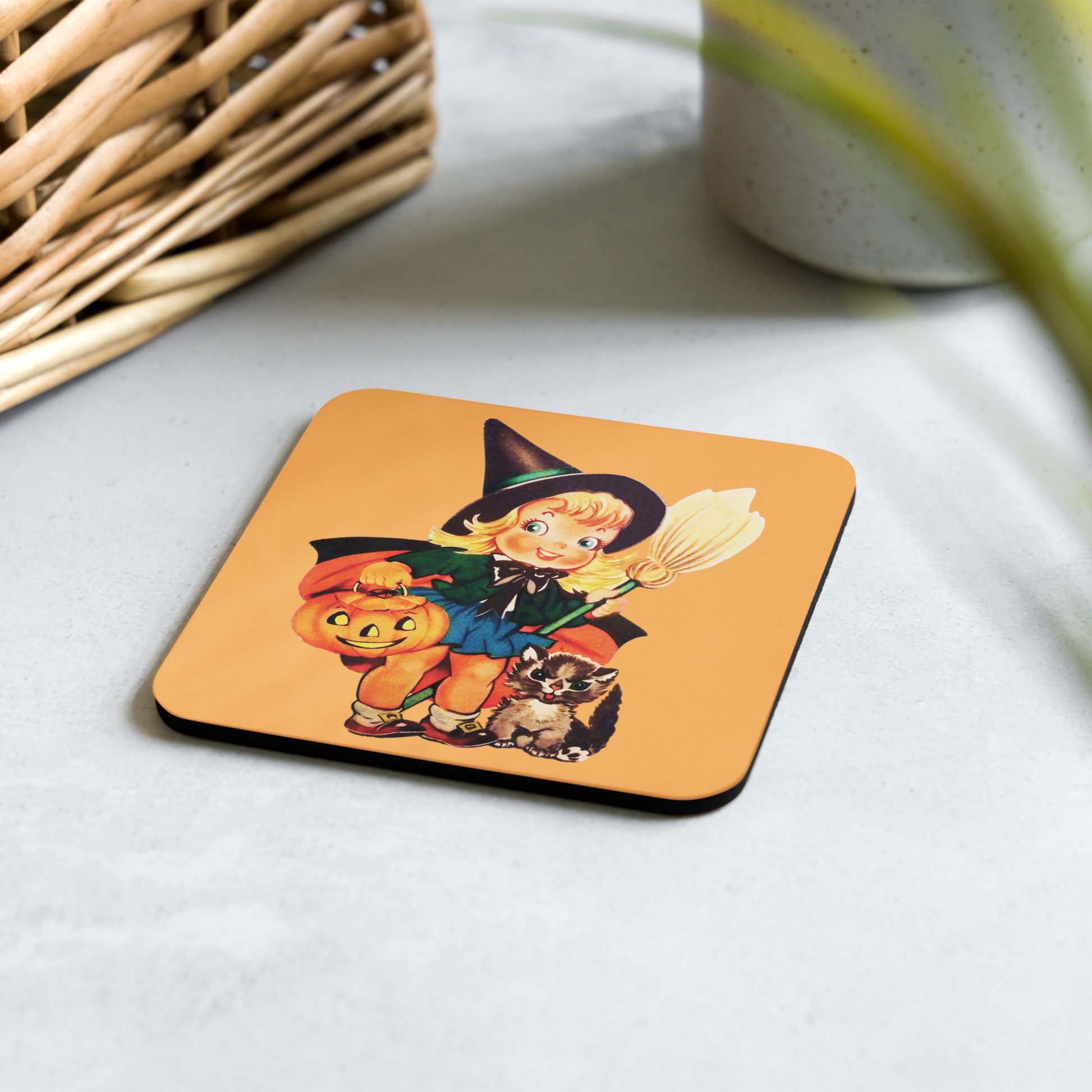 This glossy cork back coaster features an adorable retro Halloween illustration of a young witch holding a broom and jack o lantern with her brown cat sitting next to her.