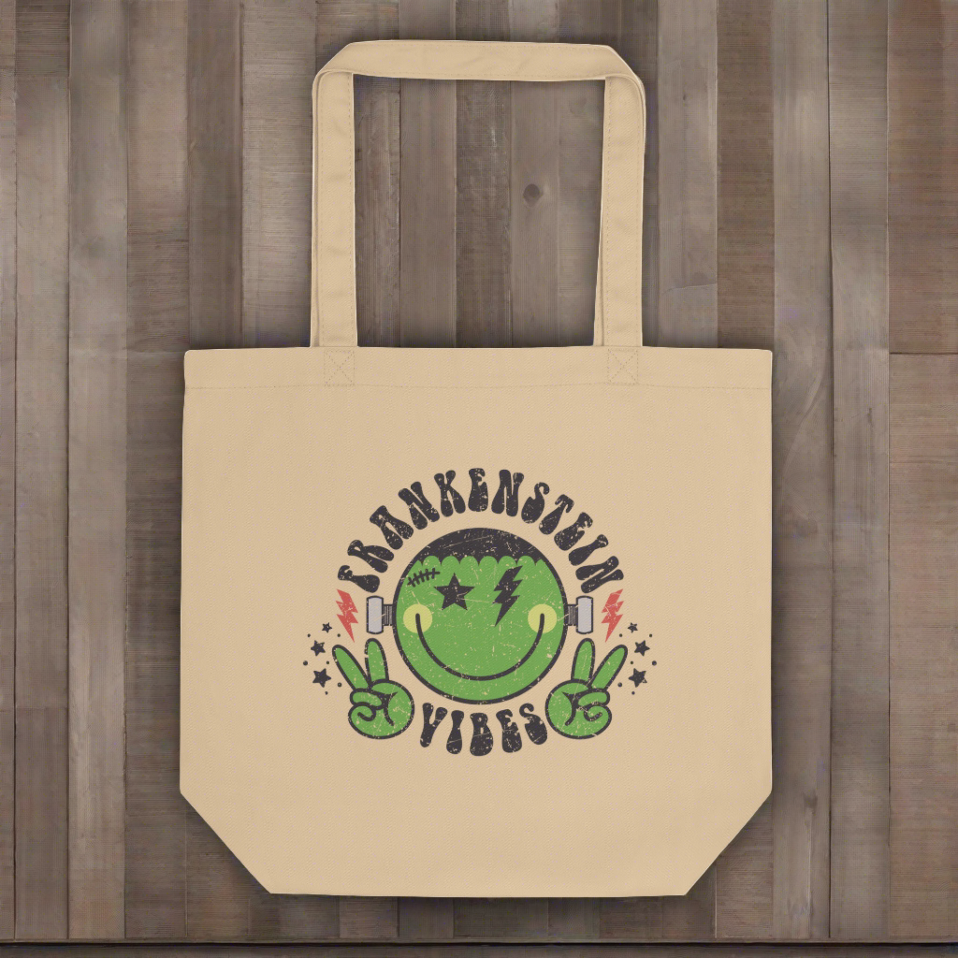 This large eco cotton tote features a distressed retro style design of Frankenstein's Monster. He's smiling and making the peace sign. The lettering Frankenstein Vibes is around his head with little stars.