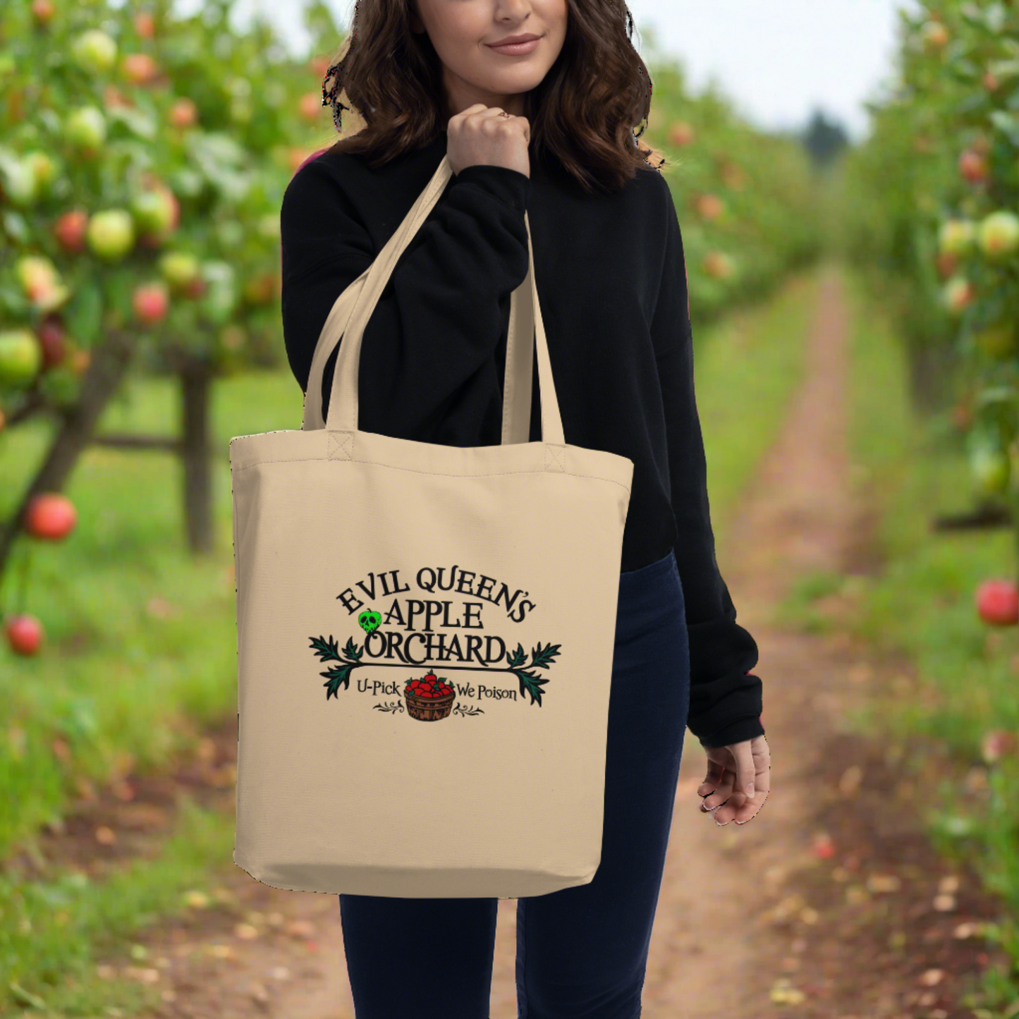 This tote bag says Evil Queen's Apple Orchard U-Pick We Poison and there is a basket of red apples with a poisoned green apple on the O in Orchard.