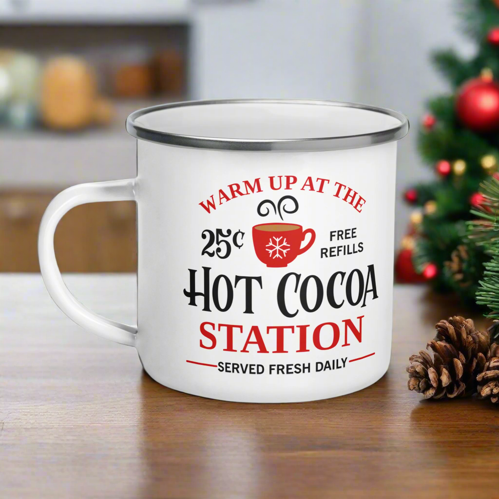 This hot chocolate camping enamel mug features a cute design that says Warm Up At The Hot Cocoa Station Served Fresh Daily.