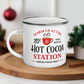 This hot chocolate camping enamel mug features a cute design that says Warm Up At The Hot Cocoa Station Served Fresh Daily.