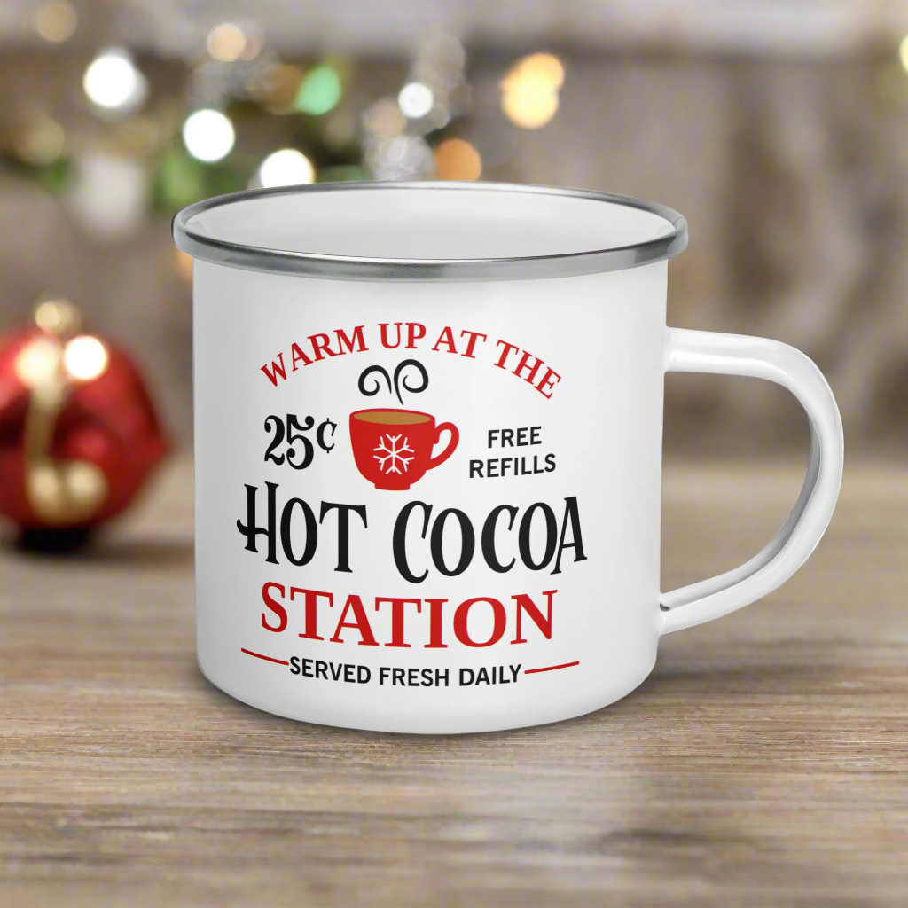 This hot chocolate camping enamel mug features a cute design that says Warm Up At The Hot Cocoa Station Served Fresh Daily.