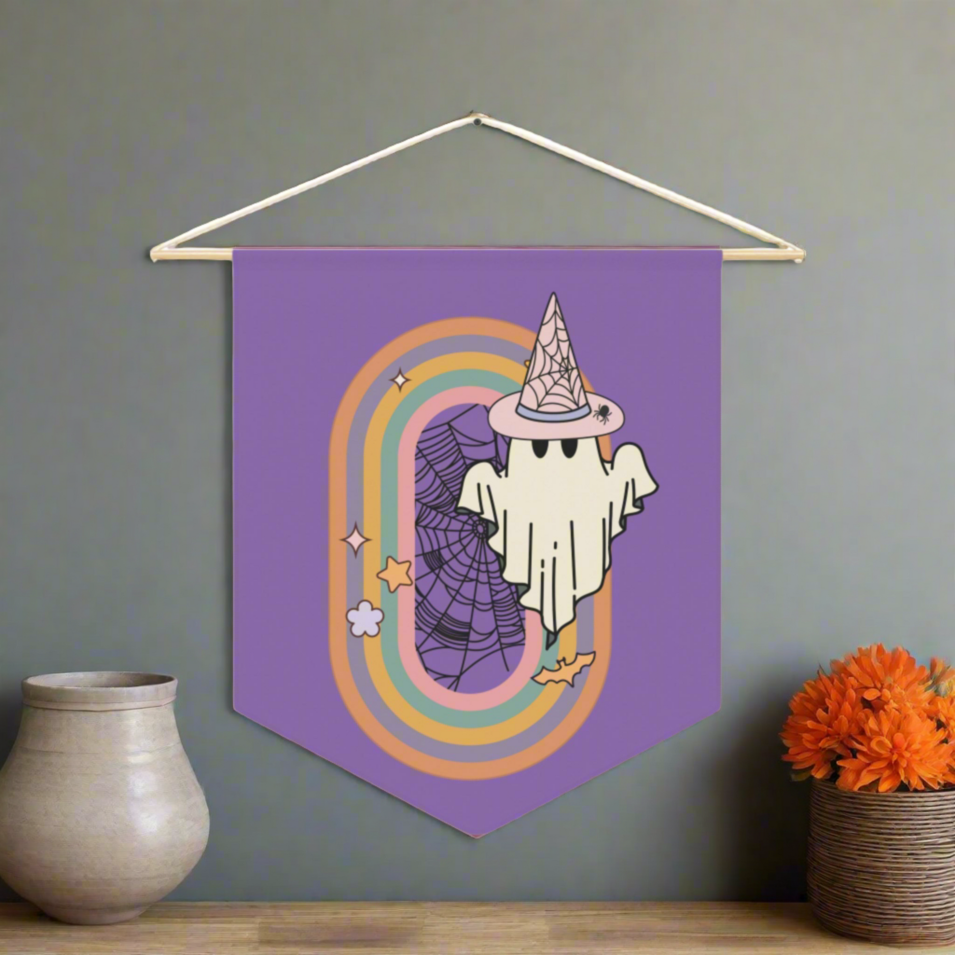 This purple pennant banner flag wall hanging features a retro boho pastel gothic style print of a ghost wearing a witch hat with a rainbow and spider web.