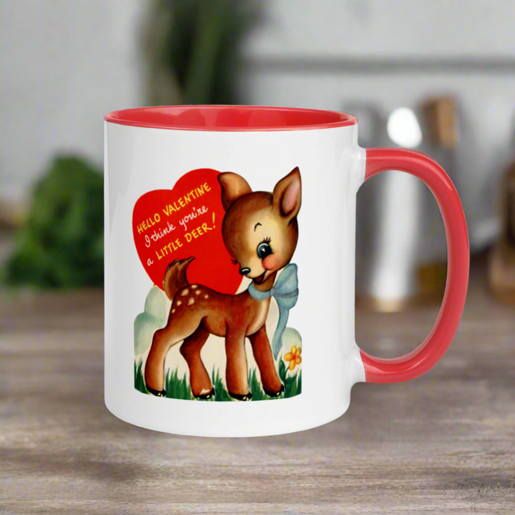 This ceramic glossy coffee mug features a retro midcentury Valentine's Day illustration of a young deer wearing a blue bow around her neck. There is a red heart that says Hello Valentine I think you're a little deer!