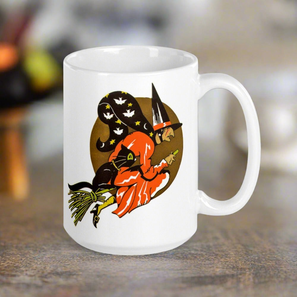 This ceramic glossy coffee mug features a retro vintage Halloween print of a witch flying on her broom with her black cat and a gold moon in the background.