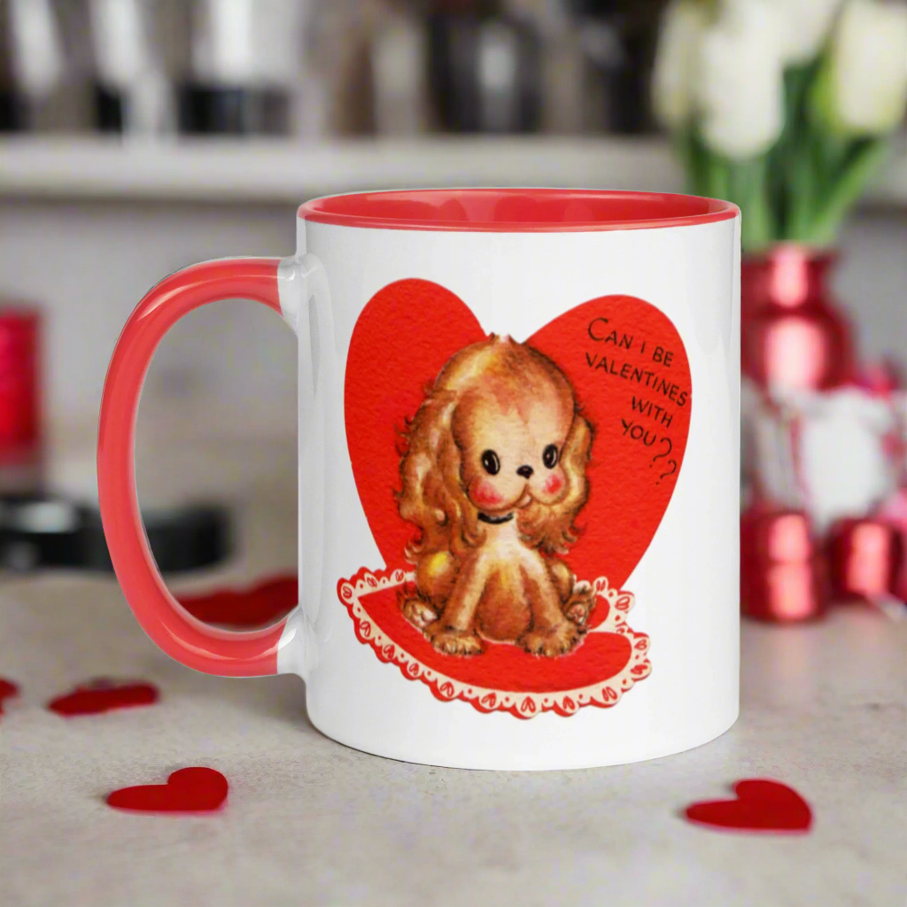 This ceramic glossy coffee cup features a vintage midcentury Valentine's Day illustration of a golden puppy sitting on a heart rug. There is a heart behind her that says Can I be Valentines with you?